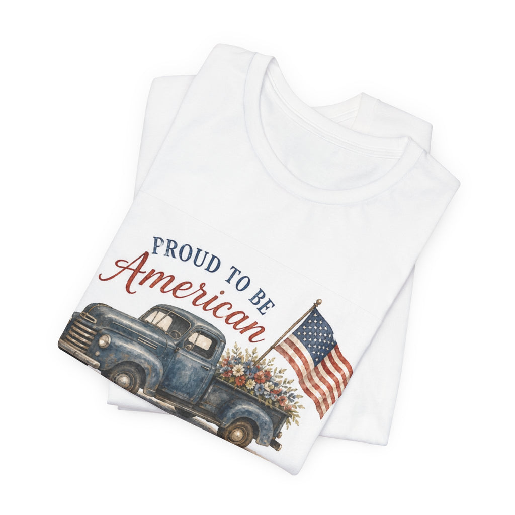 White t-shirt with vintage blue truck, flowers, and "Proud to be American" text.
